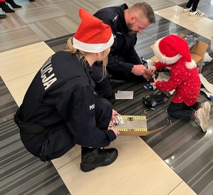 Policjanci wręczają dziecku prezent.