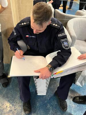 Policjant wpisuje się do księgi.